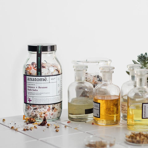 A jar of Himalayan Bath Salts next to bottles of bath supplements