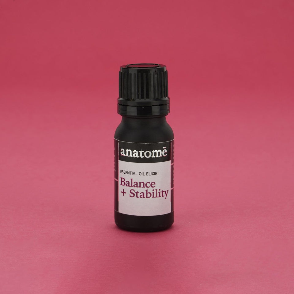 A black bottle of essential oil on a red backdrop