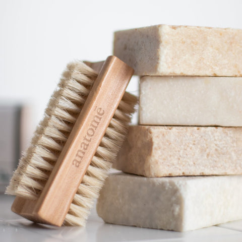 A natural bar of soap with a natural bath brush