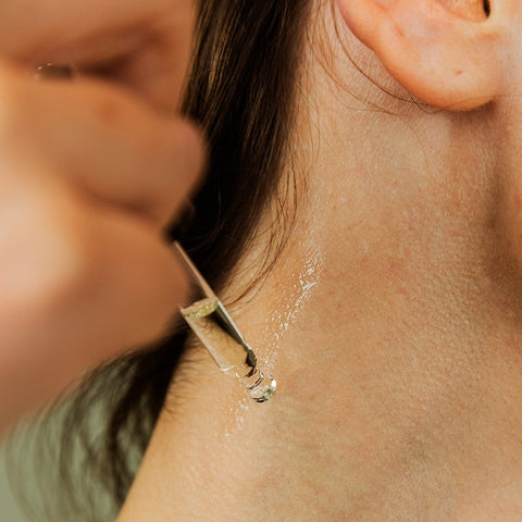 A person applying german chamomile essential oil on their neck